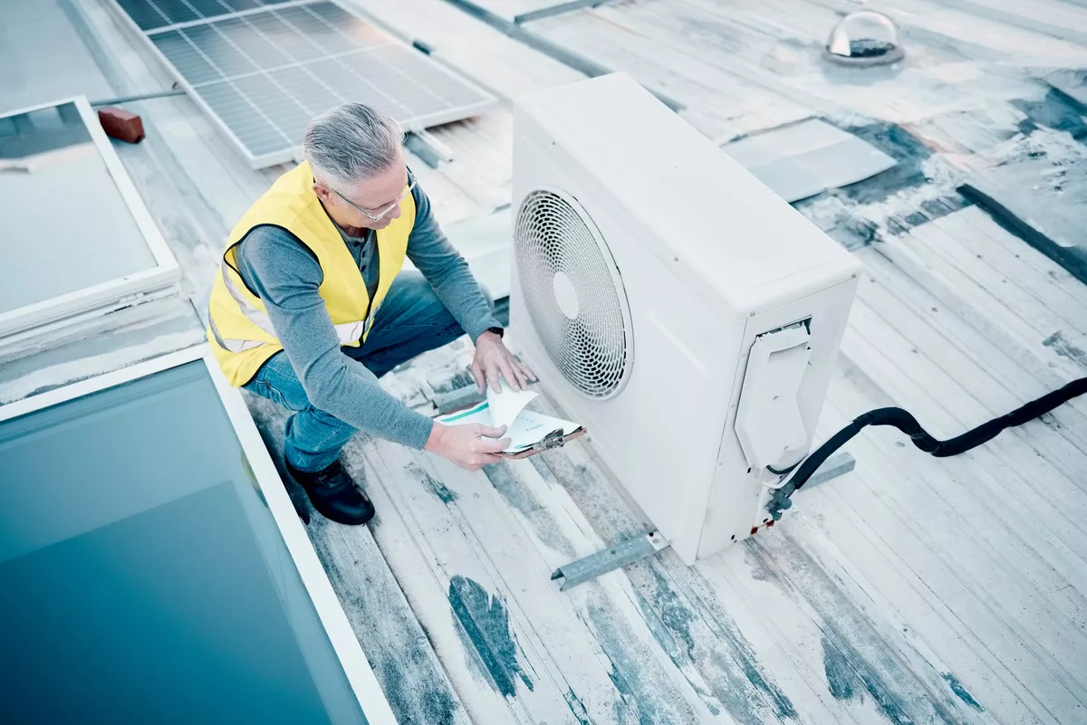 A senior HVAC inspector in a safety vest performing a comprehensive rooftop system audit near solar panels in Aurora.